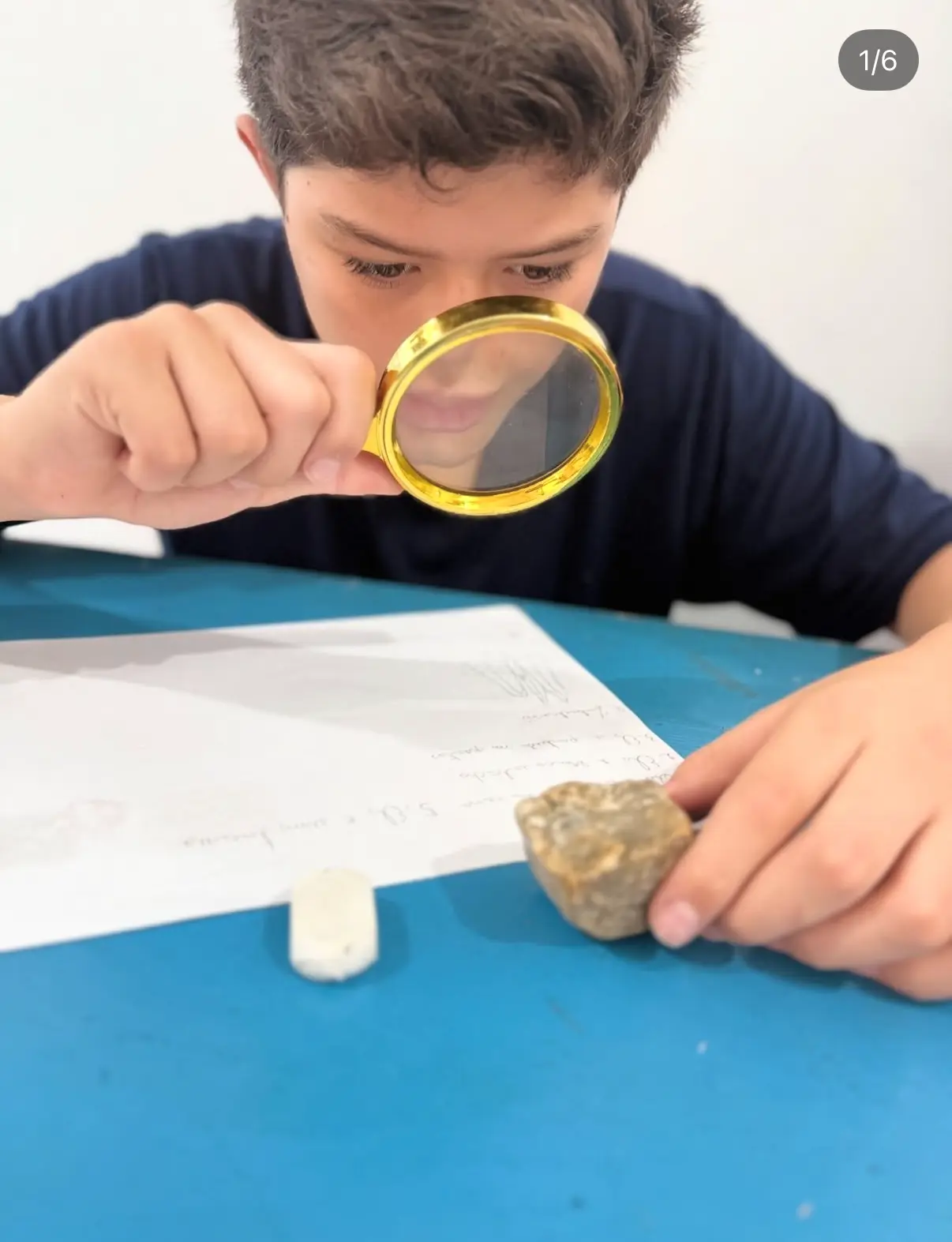 Aluno investigando materiais com uma lupa